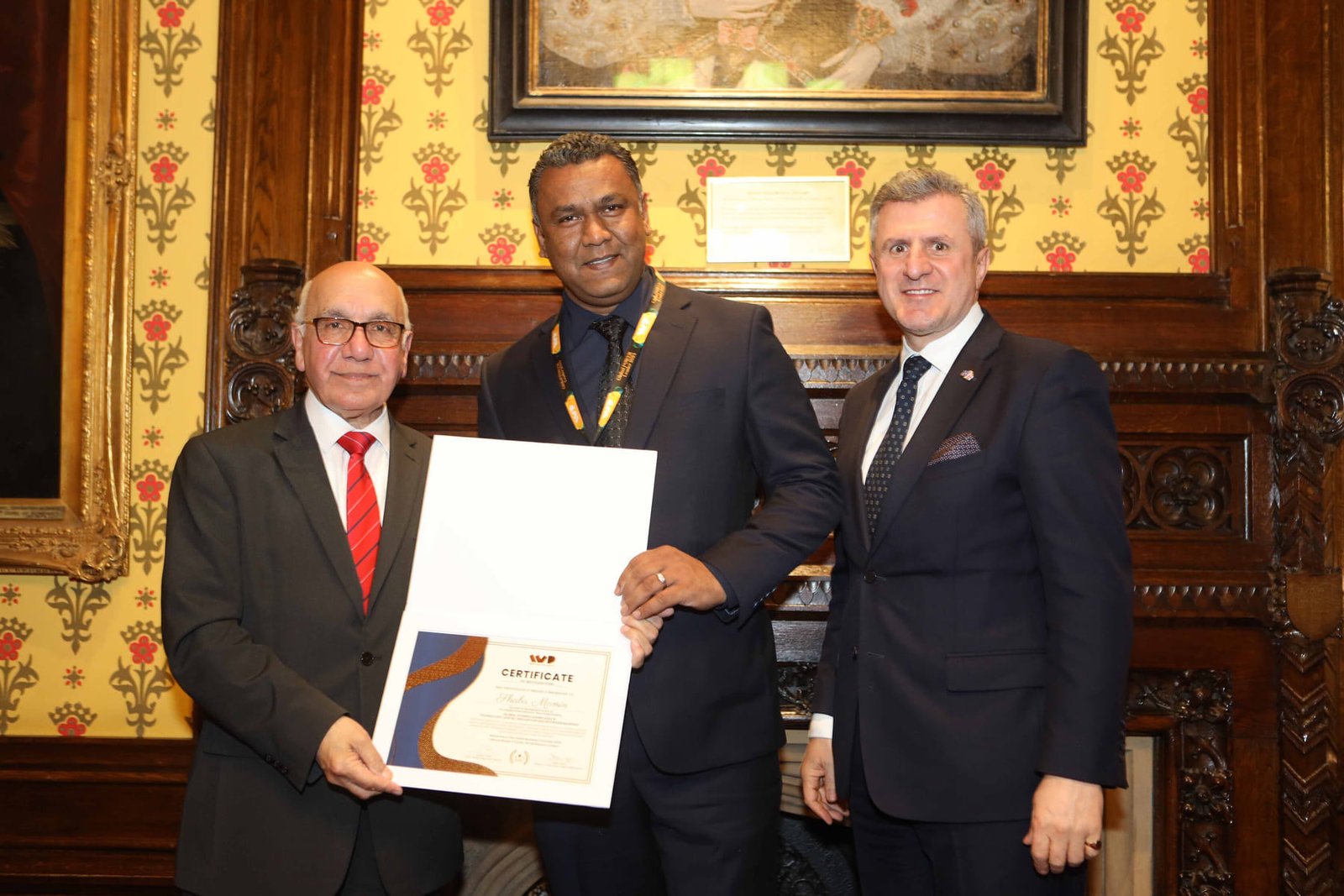 An honoree receives his certificate from the hosts in the Cholmondeley Room at the House of Lords